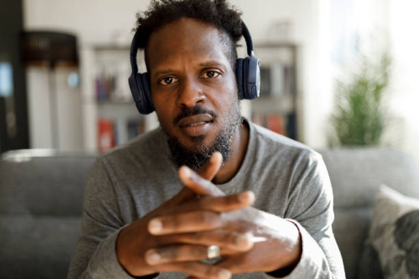 istock Man with headphones having online conference from home office 1355480051