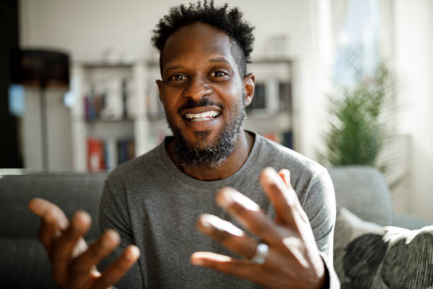 homem sorridente tendo chamada de vídeo de casa - men portrait human face smiling - fotografias e filmes do acervo