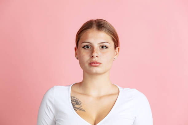 istock Close-up front camera view of young red-headed girl posing isolated over pink studio background. 1355481375