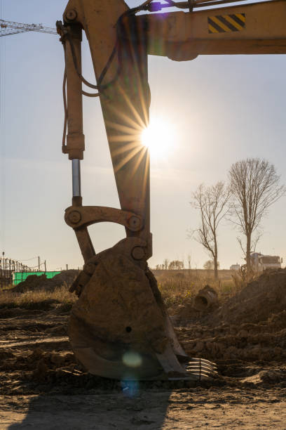 istock Vertical photo of a yellow excavator digging the ground at a construction site 1355482829