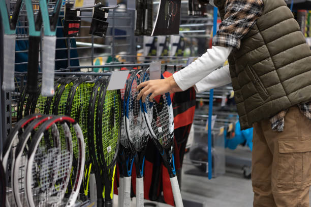 クローズアップ少年は、スポーツショップからテニスラケットを選択します。 - racket tennis professional sport ball ストックフォトと画像