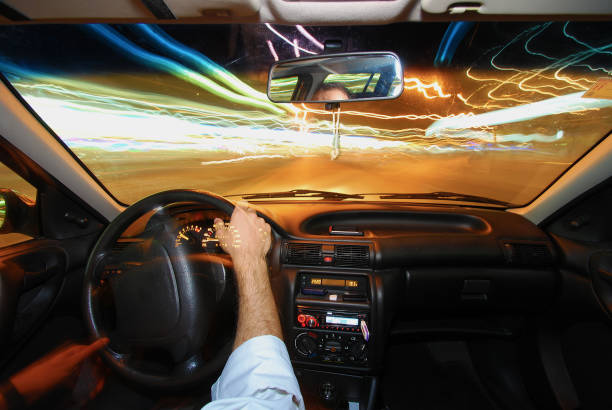 istock Man's hand driving a car with lights 1355483203