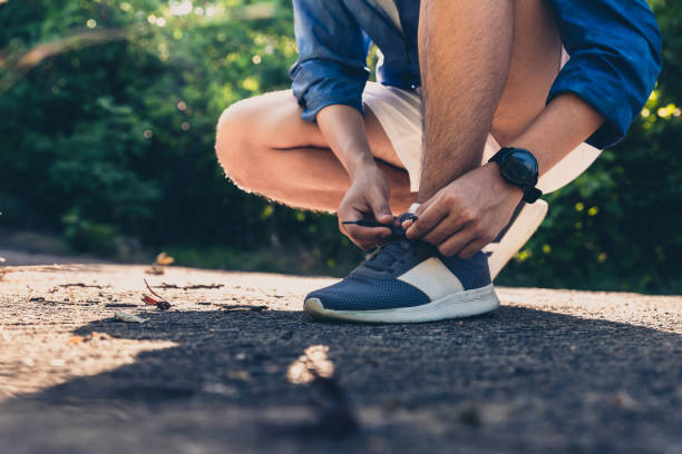 istock Hands of man tying laces running shoes before get jogging 1355487532