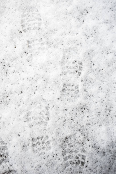 istock Footprints of human shoes in melting snow 1355487936