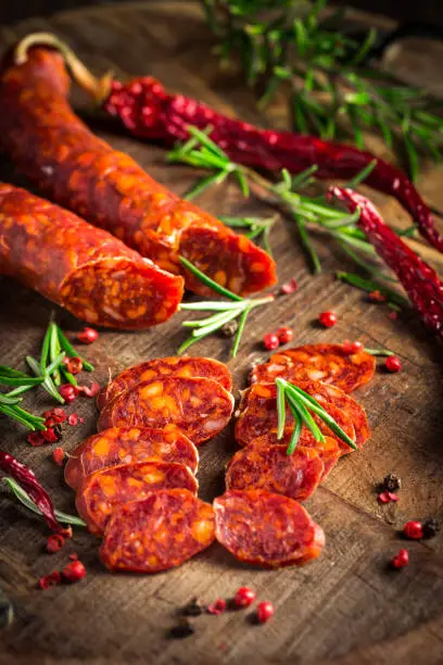 Red Spanish chorizo sausage with herbs and spices on wooden cutting board