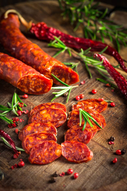 linguiça de chorizo espanhola vermelha com ervas e especiarias na tábua de corte de madeira - chorizo - fotografias e filmes do acervo