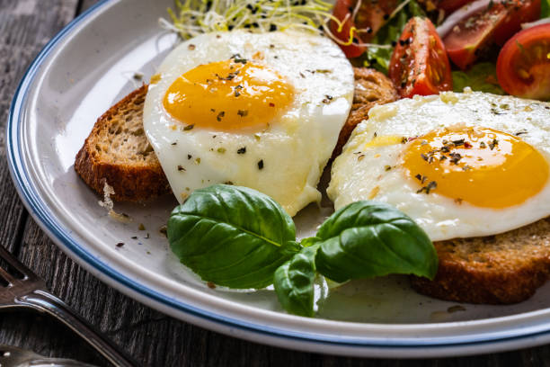 istock Continental breakfast -  sunny side up eggs on toasted bread and lettuce with cherry tomatoes on wooden table 1355495101
