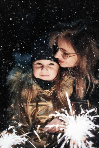 istock Mother and daughter holding burning sparklers outside 1355496268