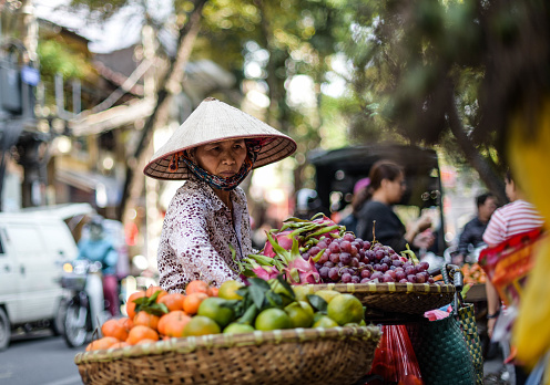 A Vietnamese fruit seller puts fruit in a bamboo basket for sale on a bicycle in Hanoi, Vietnam