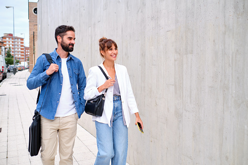 Two co-workers walking home after a day's work walking down the sidewalk