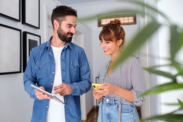 istock A man talking about work with his female co-worker in the office corridors while he holds up and shows her something on the digital tablet. 1355499361