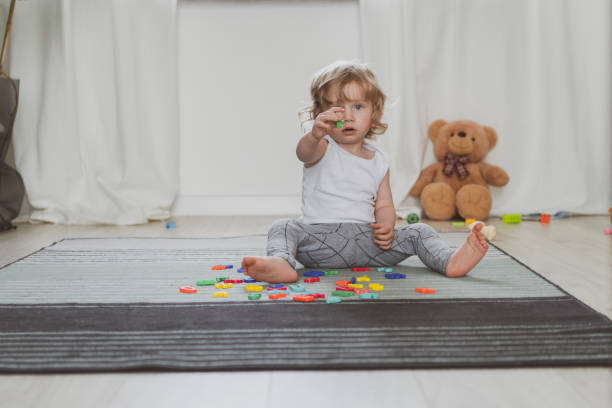 little cute toddler playing with toy letters sitting on the floor stock photo