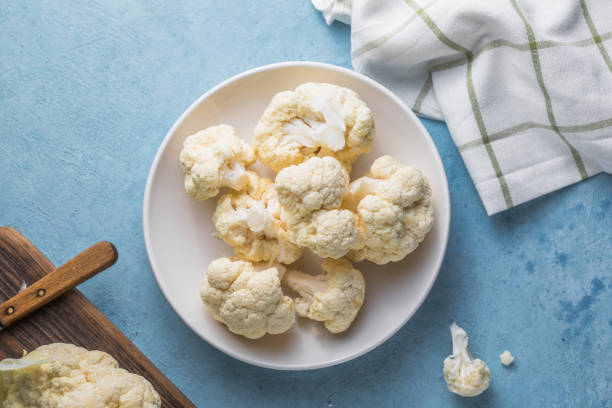 istock Raw cauliflower slices in a light bowl on a blue background with copy space. 1355501717