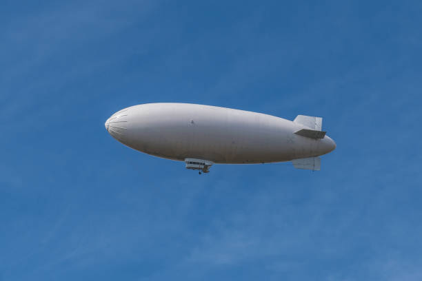 Big white zeppelin in a pale blue sky Big white zeppeling in a pale blue sky, picture made at a beautiful sunny day. blimp stock pictures, royalty-free photos & images