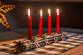 Advent wood sticks candle holder with silver stars with numbers 1,2,3,4. Four burning red candles. Christmas decoration.