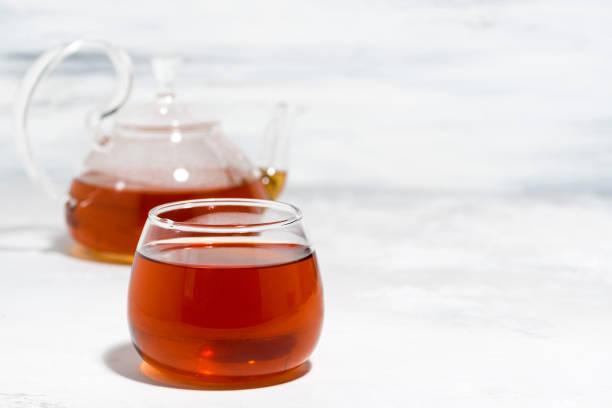 istock glass cup of tea and teapot on white background 1355507141