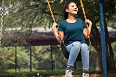 Carefree woman enjoying swinging at park