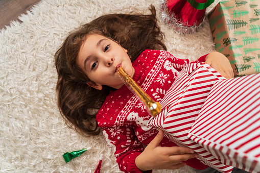 Little girl examining different Christmas presents at home