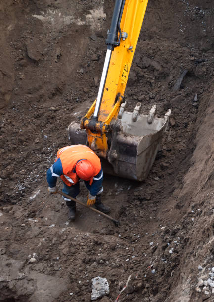KYIV, UKRAINE - May 20, 2021: Earthworks at the construction site of the city. Repair work in the city sewerage system. Worker in a special suit with a shovel