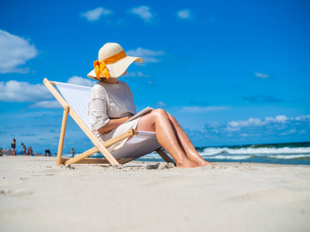 istock Woman relaxing on beach reading book 1355515705