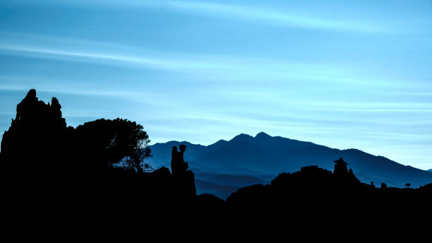 Ille-sur-Têt, France - October 11, 2021: Evening twilight and the dark silhouette of a rock formation stand out against the mountain landscape in the background.