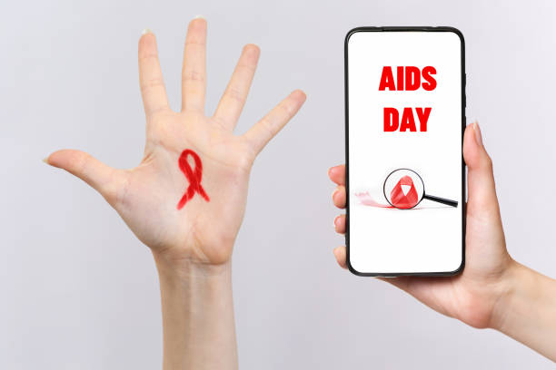 a female's hand on the right holds a smartphone. a female's left hand reaches up, with a red ribbon on her finger. white background. the concept of world aids day - world aids day stok fotoğraflar ve resimler