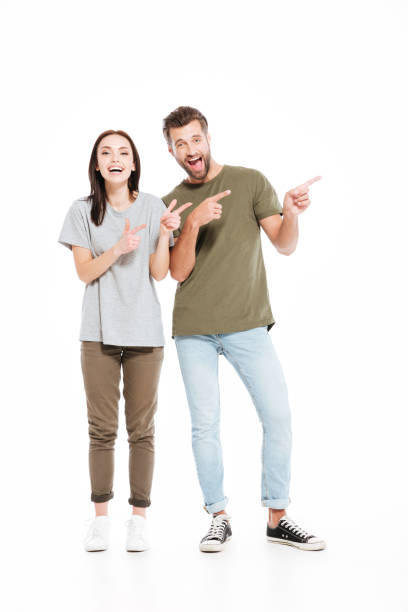 istock Smiling young loving couple pointing. 1355516869