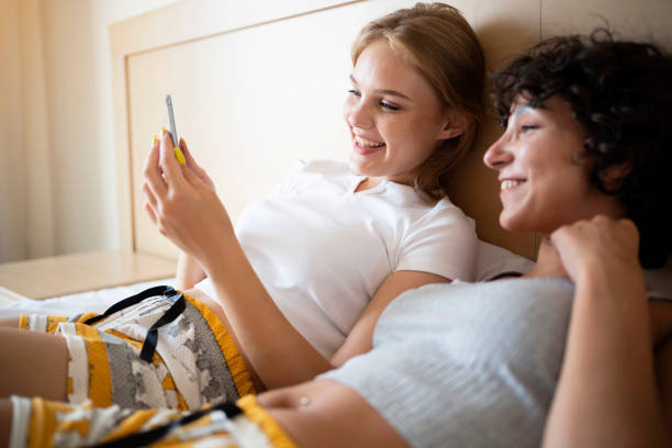 Charming Caucasian female friends looking at interesting content on mobile phone stock photo