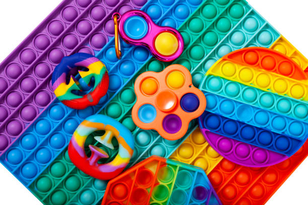 juguetes pop it fidget de moda. diferentes juguetes de goma de colores para niños. hoyuelo simple, pargo, hilandero y otros - board game spinner fotografías e imágenes de stock