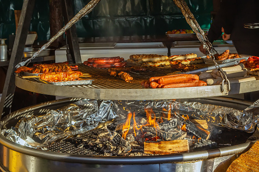 Grilled sausages of different kinds on big hanging grill at Christmas market in Frankfurt am Main, Germany