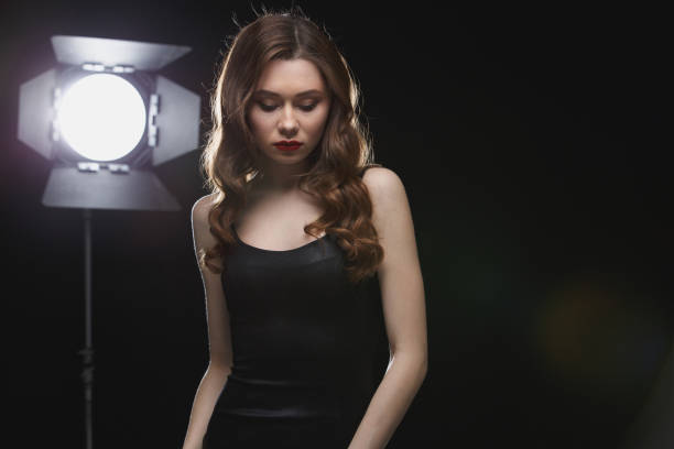 istock Pretty young woman standing near studio spotlight 1355523726
