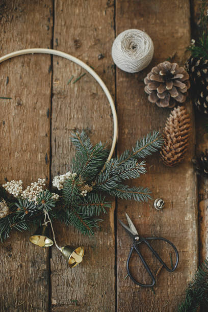 istock Modern christmas wreath, rustic flat lay. Minimal wreath with bells, fir, pine cones, scissors 1355523778