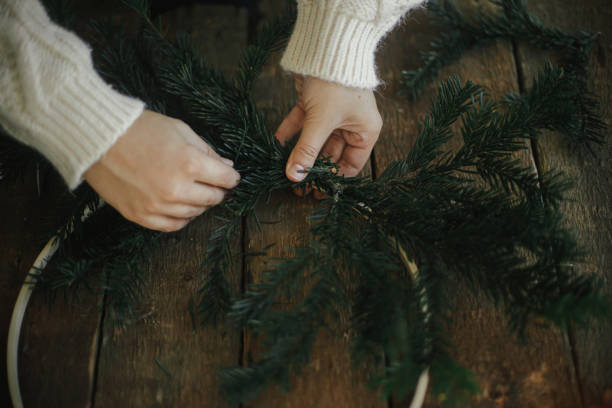 istock Hands making modern christmas wreath with fir branches on rustic table with round wooden hoop 1355525045