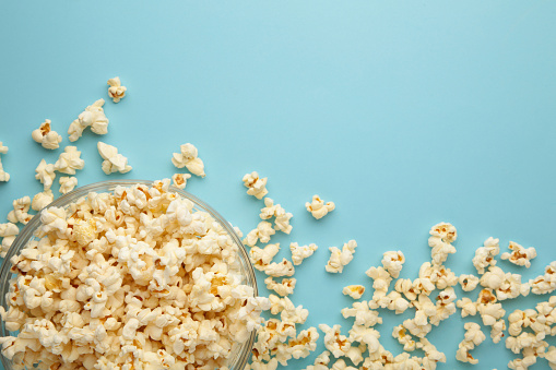 Popcorn in glass bowl on blue background.Top wiew.