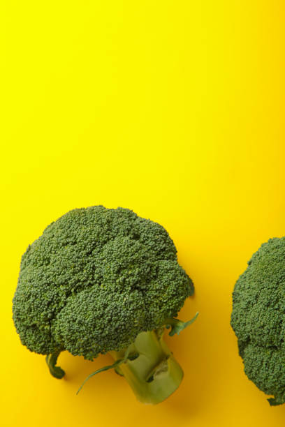 istock Broccoli cabbage on a yellow background. Pattern of fresh broccoli cabbage. Vertical photo, 1355526265