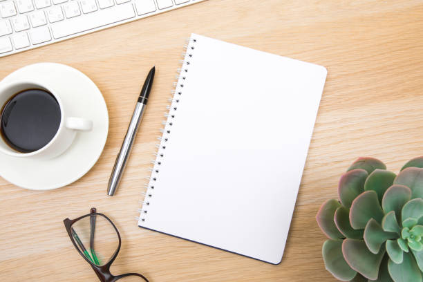 istock open notepad, cup of coffee, pen ,moose, keyboard on wooden background spiral notebook on table Business, planning, education, morning life working from home concept Top view Flat lay Mock up 1355527556
