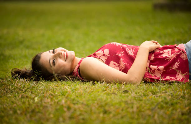 Thoughtful young woman lying down and relaxing on grass at park