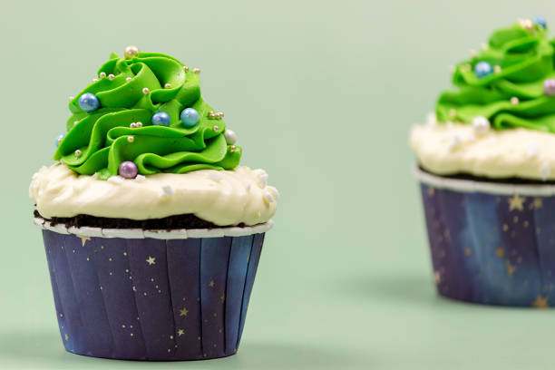 istock Christmas cupcakes against green background. Selective focus, place for text. 1355528361