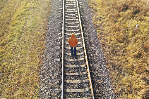 Loneliness concept. A man walks along the railway tracks, running away from himself.