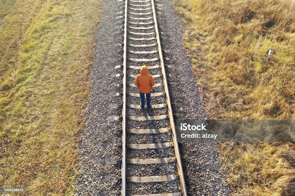 Loneliness concept. A man walks along the railway tracks, running away from himself. Loneliness Stock Photo