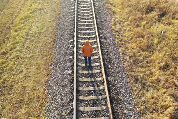 Photo of Loneliness concept. A man walks along the railway tracks, running away from himself.