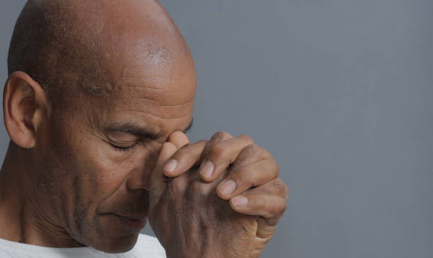 istock man praying with hands stock photo 1355531199
