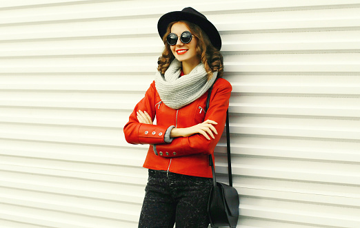Portrait of beautiful young woman posing wearing a red jacket, black round hat on white background