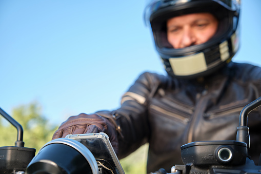 Motorcyclist out of focus using smartphone while seated on motorcycle