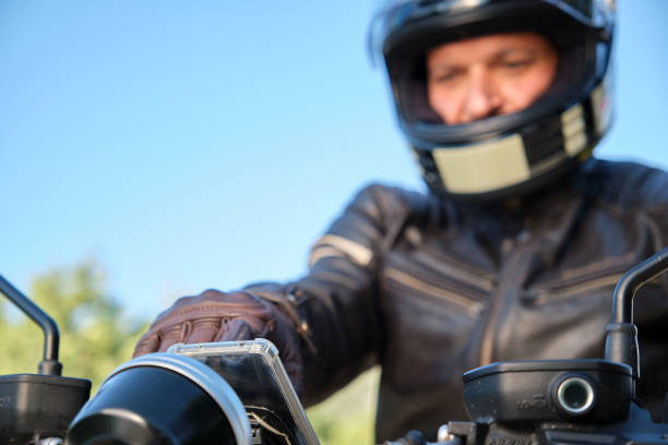 Motorcyclist out of focus using smartphone on motorcycle stock photo