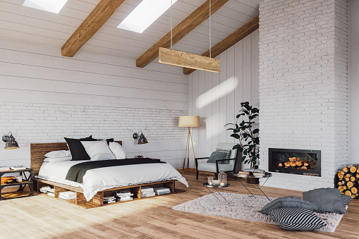 Interior of a Scandinavian style attic bedroom with fireplace in a cottage house.
