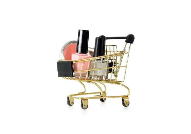 Photo of Shopping trolley full of make up and cosmetic goods, isolated on white background. Black friday concept. Sale and discount. Goods for women. Closeup of a basket with products for make-up.
