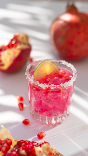 Summer cocktail with pomegranate and ice with palm shadow stock photo