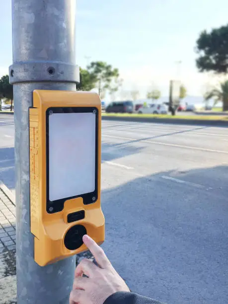 Finger pushing stoplight push button at the roadside. Traffic light control box