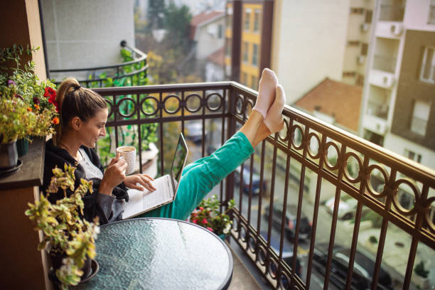 istock Young woman using laptop on balcony at morning 1355539022